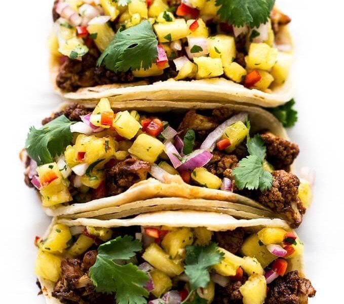 A row of three Fourth of July BBQ cauliflower tacos topped with pineapple and a dash of chopped cilantro