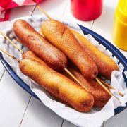 A collection of Fourth of July corn dogs in a blue basket lined with paper