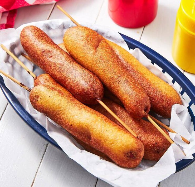 A collection of Fourth of July corn dogs in a blue basket lined with paper