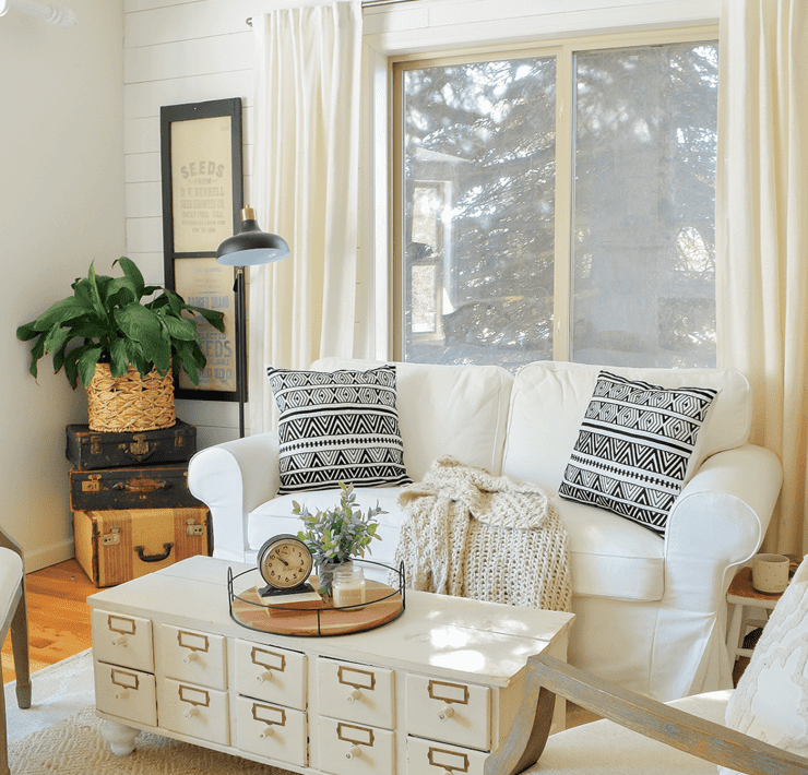 sarah joy blog's Seating area with white couch, plants, and throw pillows against a window