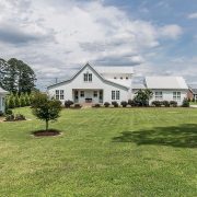 The front view of a white farmhouse shaped like a classic barn.
