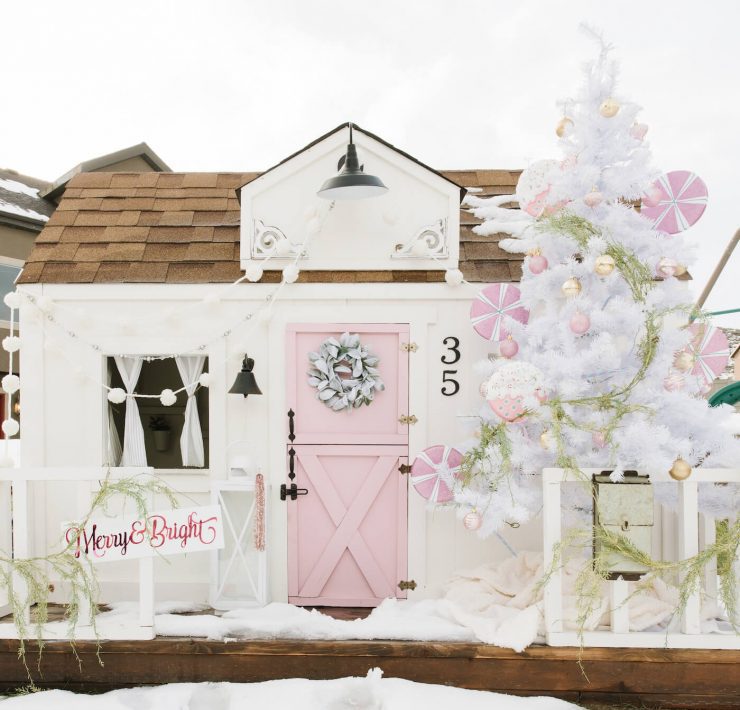 Exterior of playhouse with pink door and white Christmas tree