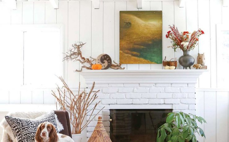 white brick fireplace next to gray chair with dog