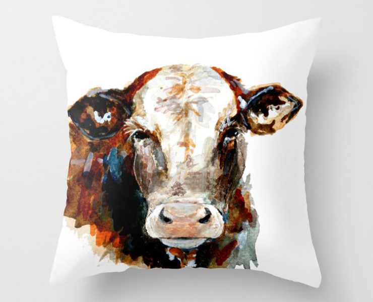 White pillow with the face and neck of a brown and white cow.