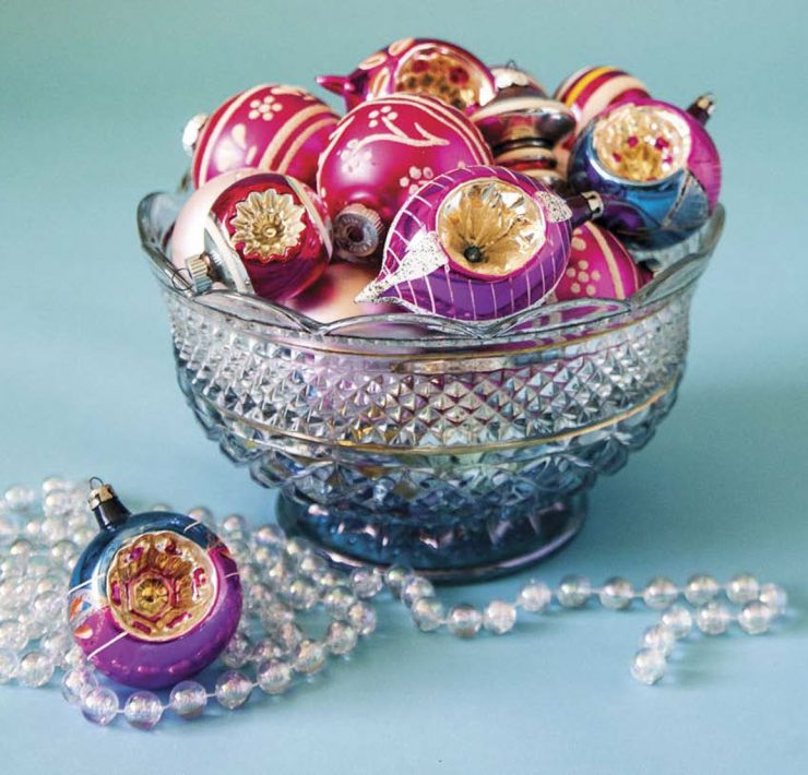 A beautiful clear glass bowl is full of colorful collectible glass ornaments.