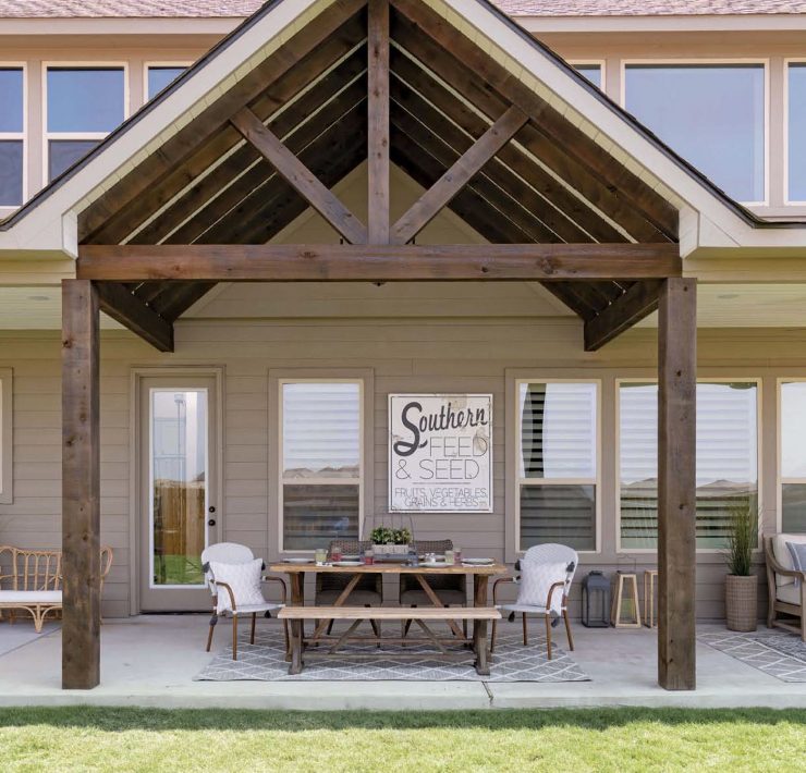 The exterior of this Texas farmhouse has a broad triangular archway over a table ready for guests!