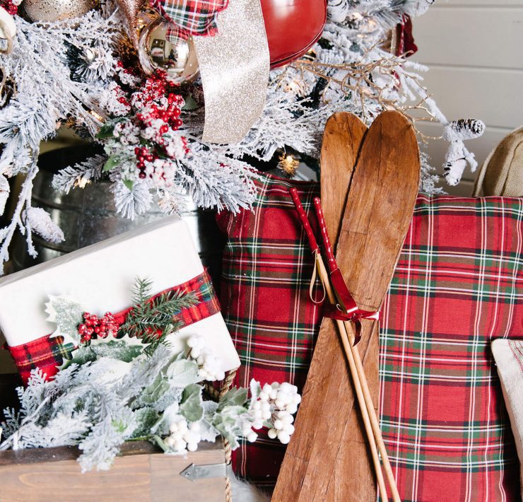 White gift wrap on packages with red embellishments under a Christmas tree