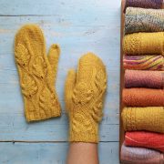 Two mustard-colored knit mittens with a leafy design knitted into them in true country winter fashion.