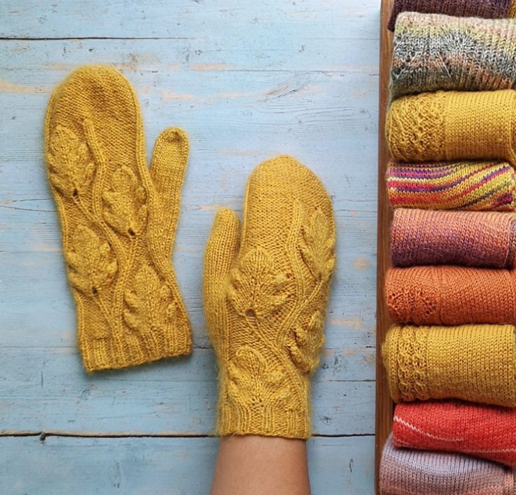 Two mustard-colored knit mittens with a leafy design knitted into them in true country winter fashion.