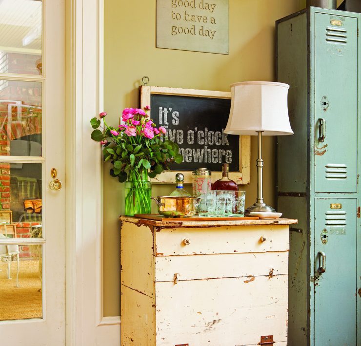 A cream-colored vintage desk with a lamp, bouquet of flowers and teal vintage lockers next to it demonstrates how to decorate with what you already have.