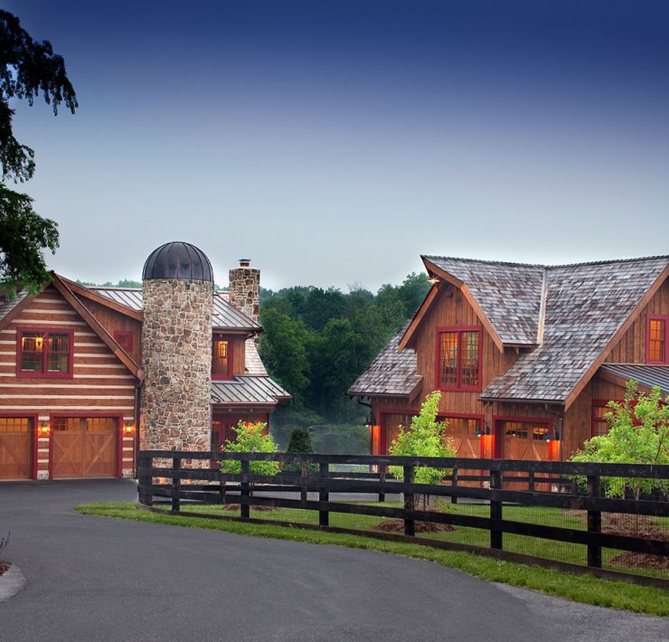 The exterior of two separate wooden farmhouse buildings, including a stone silo and a surrounding fence.