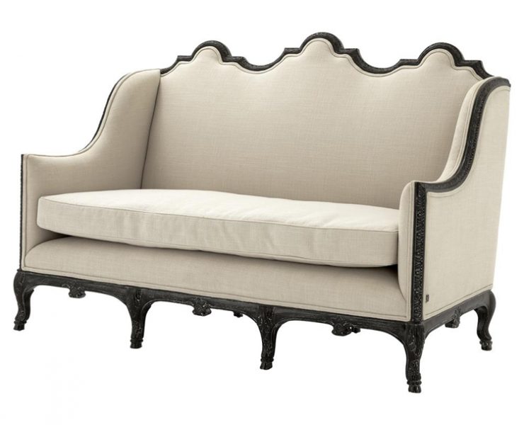 This piece of farmhouse furniture is a antique-style love seat with cream fabric and black edging.