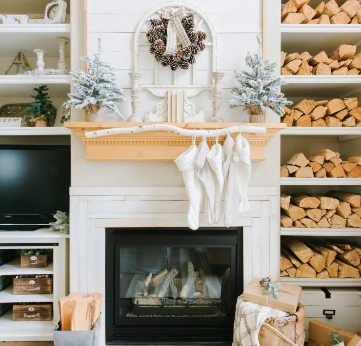 Fireplace with wood mantel, stockings and built-in shelves full of firewood.