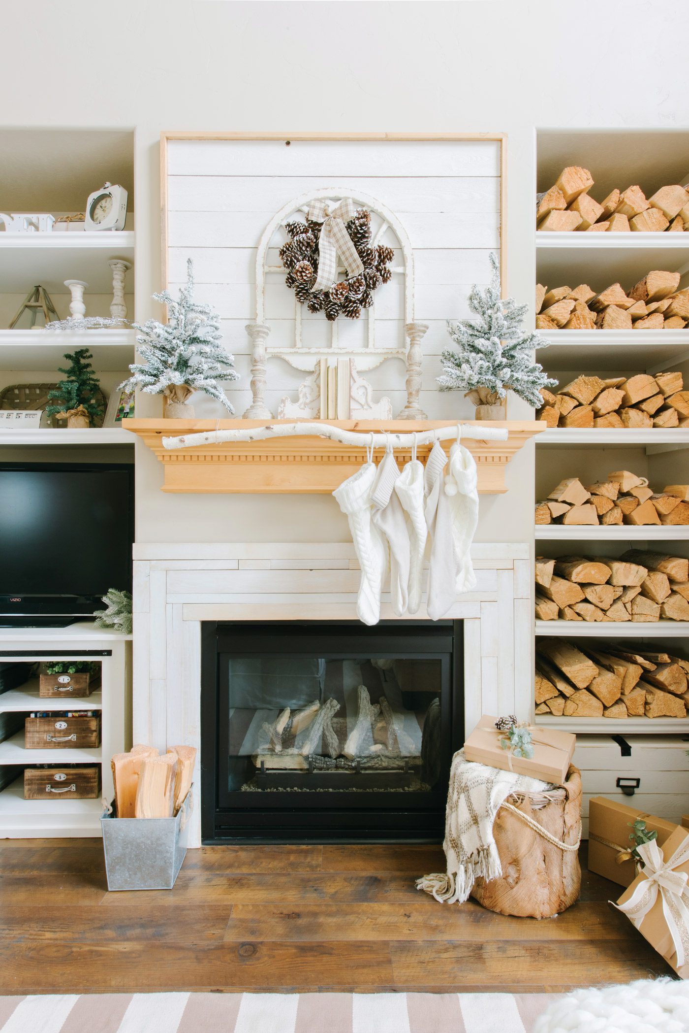 Fireplace with wood mantel, stockings and built-in shelves full of firewood.