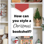 Open shelves in a Christmas bookcase decorated with Christmas decor, including a gingerbread house with an elf-on-the-shelf on the roof.