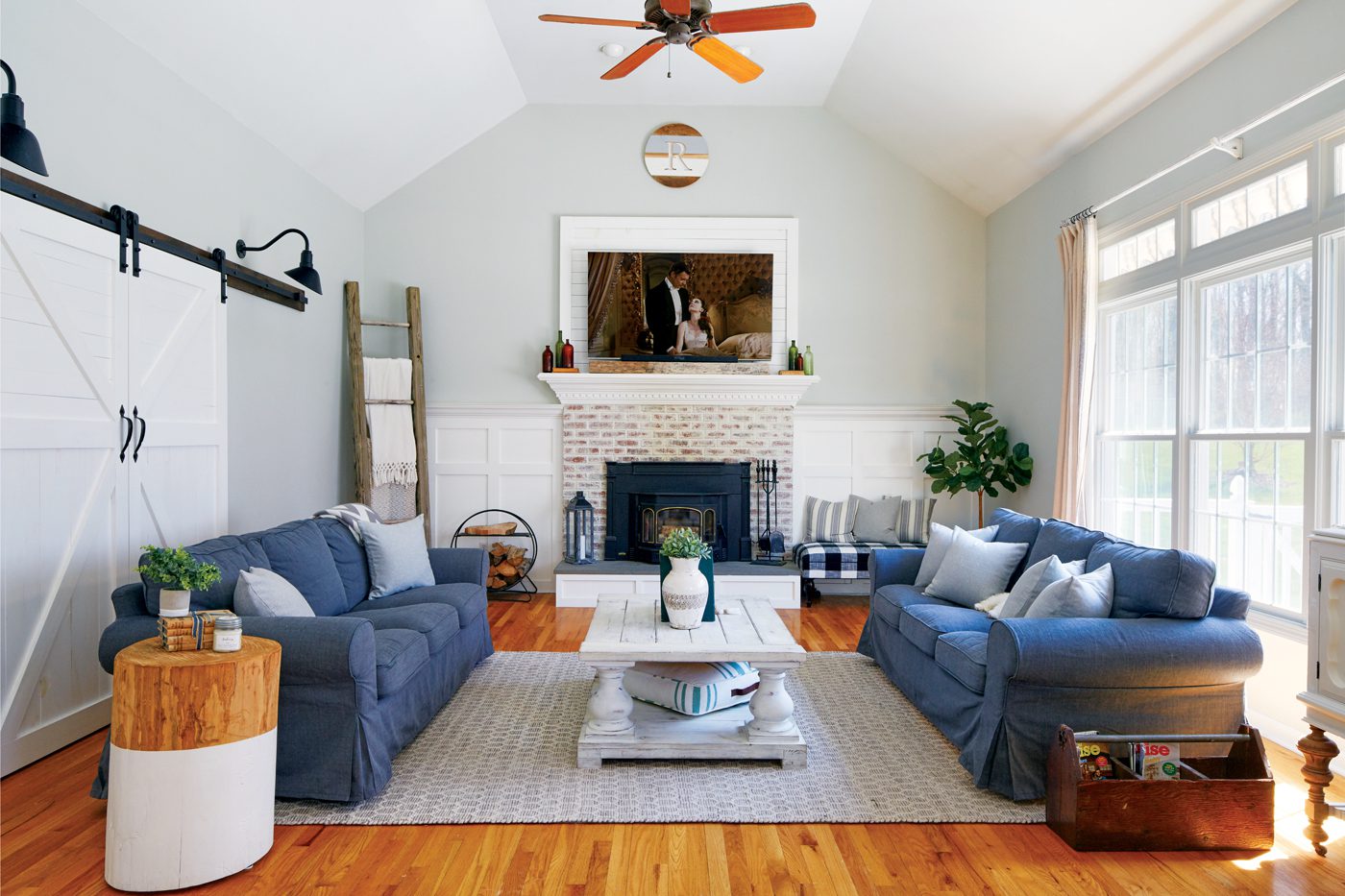 A modern farmhouse with white interior space and two large blue counchs facign each other.