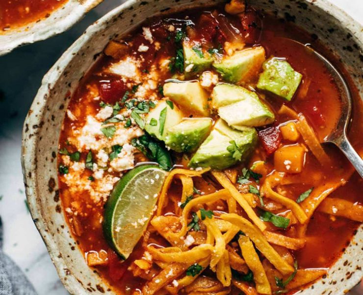 Sweet potato soup with shredded cheese, avocado pieces and a lime wedge on top, one of our favorite farmhouse soup recipes.