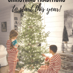 Two children beside the glowing Christmas tree in red and white striped pajamas.