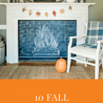 A fireplace frames a chalkboard drawn with chalk to look like a buring fire. On the mantel is a wreath of fall leaves and a white pumpkin.