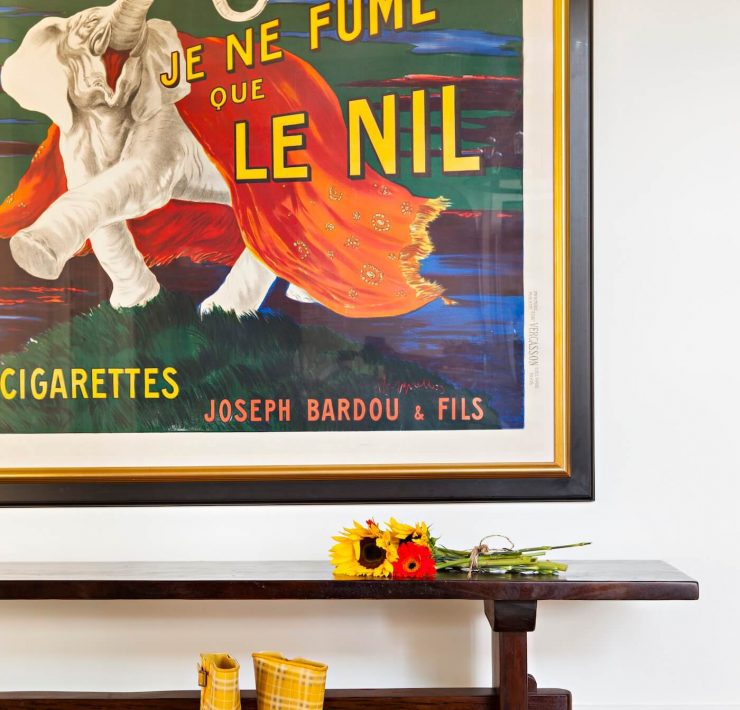 vintage poster on wall in front of bench with sunflowers