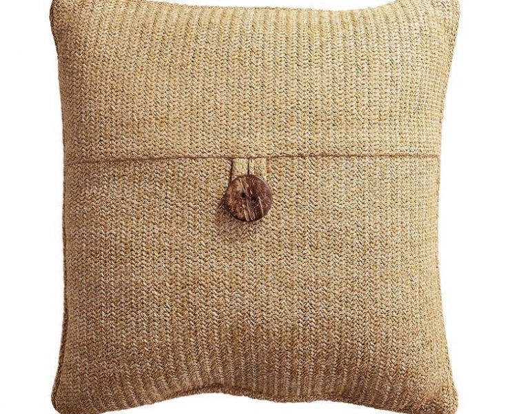 A pillow in a rustic color redolent of burlap and with a button in the middle