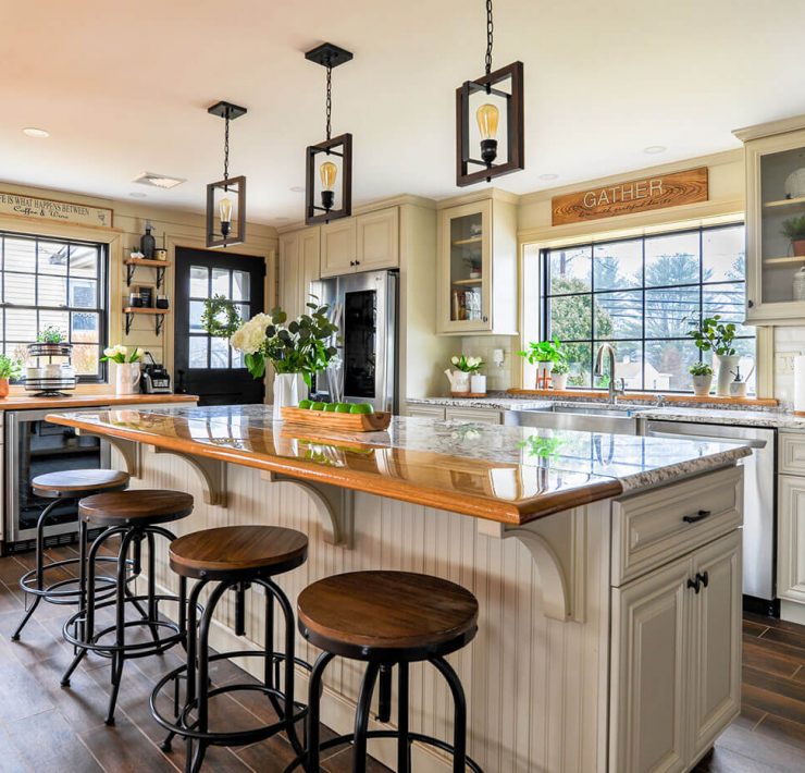 Open kitchen with island and bar stools, white cabinets and hanging pendant lights