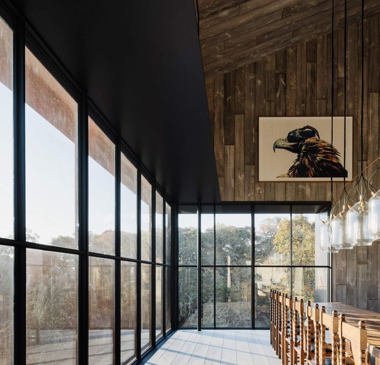 Dining room in modern barn home with wall to wall windows and wood paneling