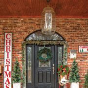 Front door with Christmas garland and sign art and Christmas decor