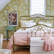 bedroom with floral wallpaper and vintage metal bedframe