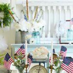 4th of July décor centerpiece with candlesticks, vintage weight, and mini flags.