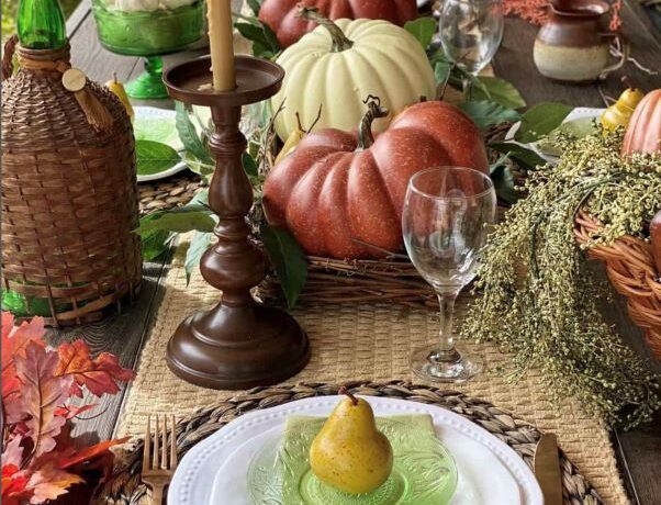 Large Cinderella variety pumpkins and ghost pumpkins sit atop a centerpiece that fills the rest of the table with harvest looks